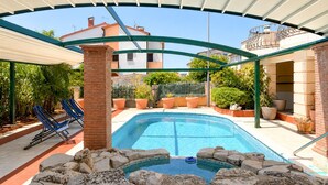 A swimming pool with a stone border, surrounded by lounge chairs and potted plants. - Awesome home in Porec (Porec)
