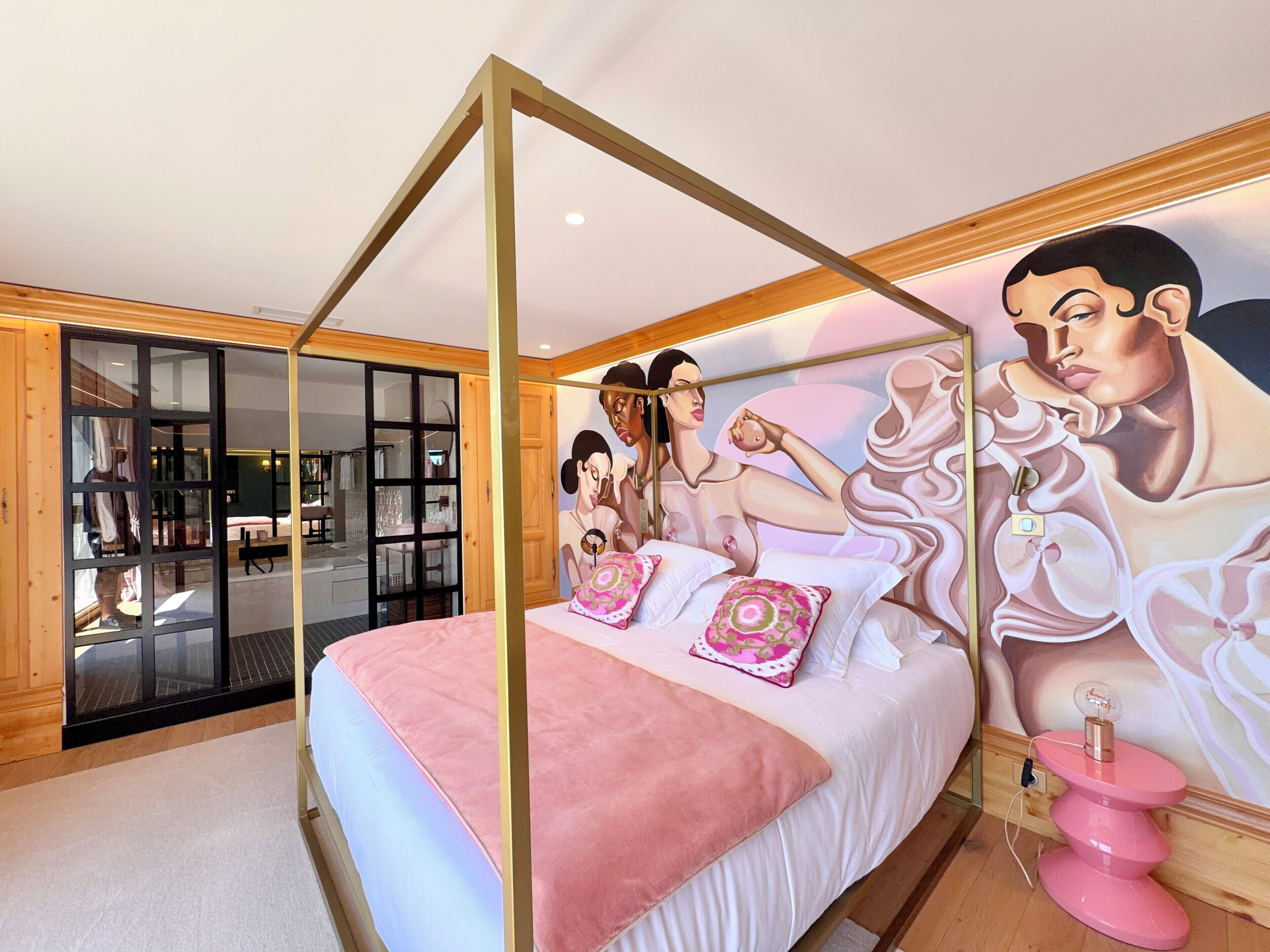 Un dormitorio con cama con dosel, un mural grande y vistas al baño.