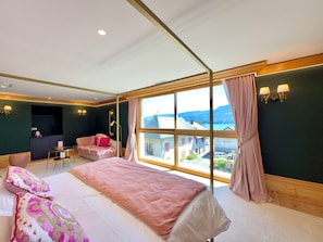 A hotel room with a bed, a desk, a chair, and a view of the outside.