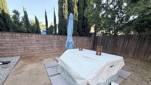 A covered patio with a table, steps, and a brick wall. - Boho luxury 2 master suites, huge yard (Alhambra)