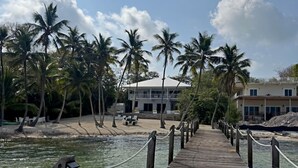 A wooden pier leading to a beachfront property with palm trees and a clear sky. - Casa del Mar (Key Largo)