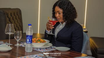 A dining table with a bottle of water, a glass of red drink, and a plate of food.