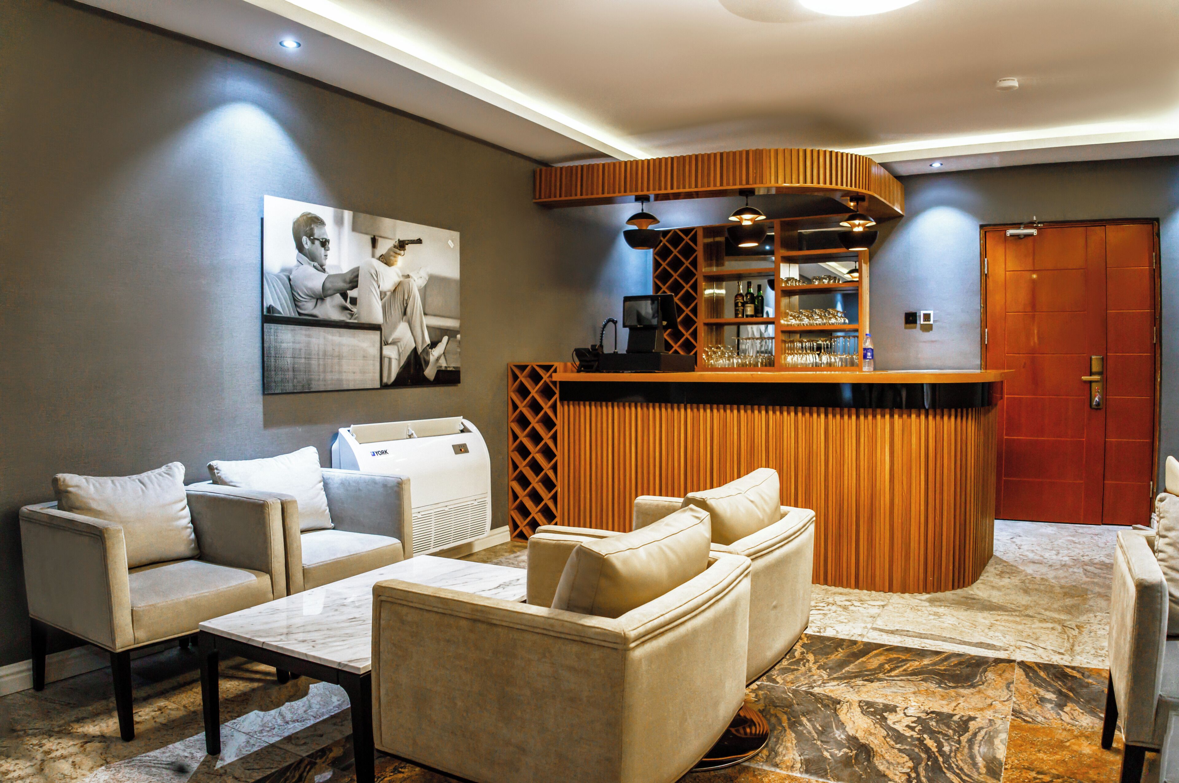 A modern living area with a bar, sofas, and a fireplace.