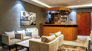 A modern living area with a bar, sofas, and a fireplace.