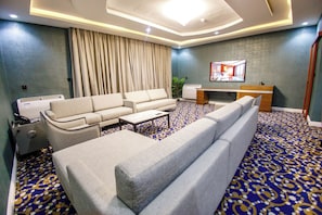 A hotel room with a sofa, a coffee table, a TV, and a patterned carpet. - Swisse International Rancho Valeria (Warri)