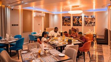 A dining area with tables set for a meal, a ceiling with recessed lighting, and wall-mounted artwork.
