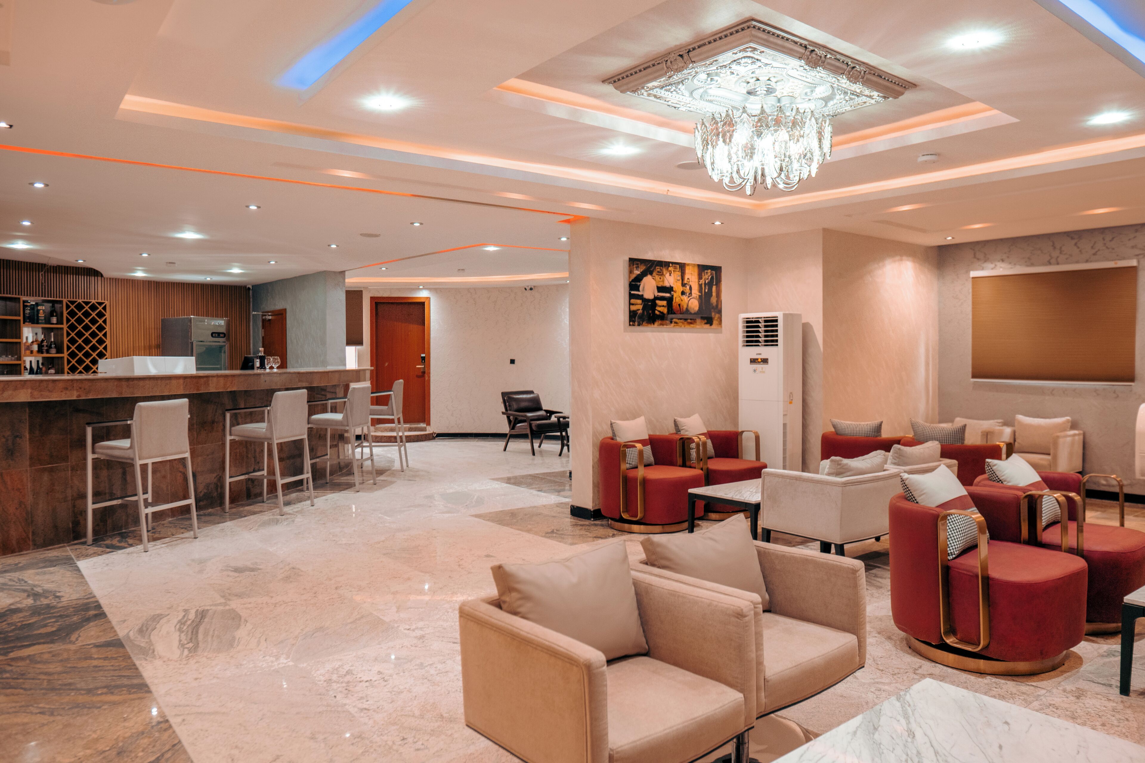 Vestíbulo de hotel con zona de bar, disposición de asientos y una araña.