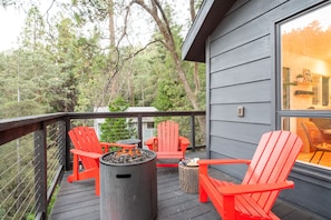 A deck with red chairs, a fire pit, and a table. - Amazing 5 bedroom house in peaceful Lake Arrowhead getaway (Lake Arrowhead)