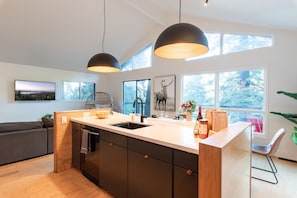 A modern kitchen with a central island, large windows, and pendant lighting. - Amazing 5 bedroom house in peaceful Lake Arrowhead getaway (Lake Arrowhead)