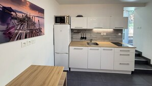 A modern kitchen with white cabinets, a microwave, a sink, and a wooden table. - Studio moderne, climatisé, avec grande terrasse - La Garde (La Garde)