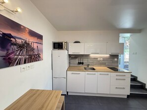 Una cocina moderna con armarios blancos, microondas, lavaplatos y una mesa de madera.