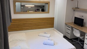 A hotel room with a bed, a desk with a computer, a mirror, and an air conditioning unit. - Studio moderne, climatisé, avec grande terrasse - La Garde (La Garde)