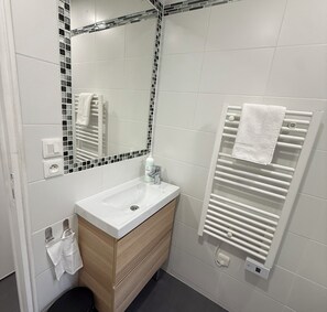 A bathroom with a white sink, a mirror with a mosaic border, a towel rack, and a towel hanging on the wall. - Studio moderne, climatisé, avec grande terrasse - La Garde (La Garde)