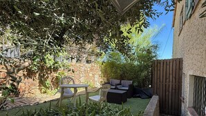 A patio area with outdoor furniture, a stone wall, and a variety of plants. - Studio moderne, climatisé, avec grande terrasse - La Garde (La Garde)