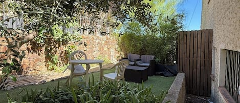 A patio area with outdoor furniture, a stone wall, and a variety of plants.