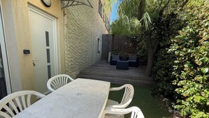 Eine Terrasse mit Tisch und Stühlen, ein Holzdeck und eine Steinmauer.