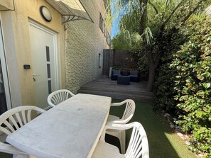 A patio with a table and chairs, a wooden deck, and a stone wall. - Studio cosy dans villa, climatisé, terrasse - La Garde (La Garde)