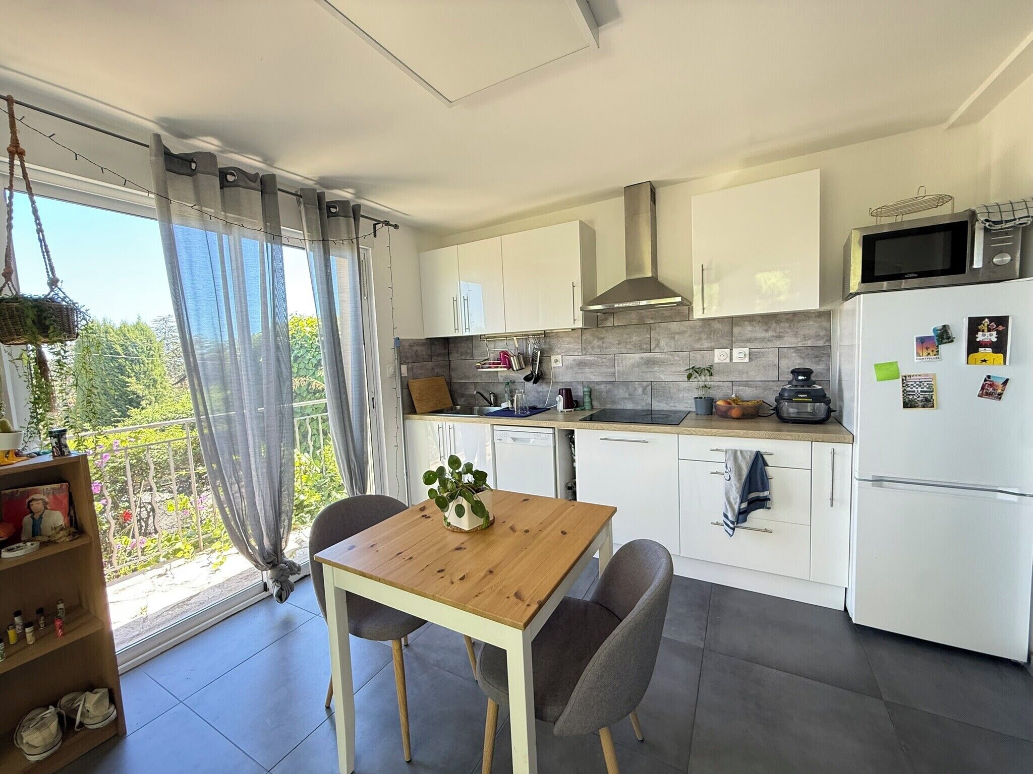 Een moderne keuken met witte kasten, een houten tafel en uitzicht op groen.