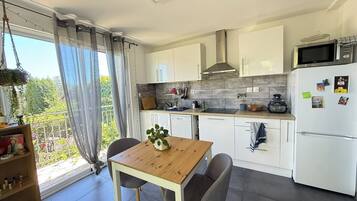 Een moderne keuken met witte kasten, een houten tafel en uitzicht op groen.