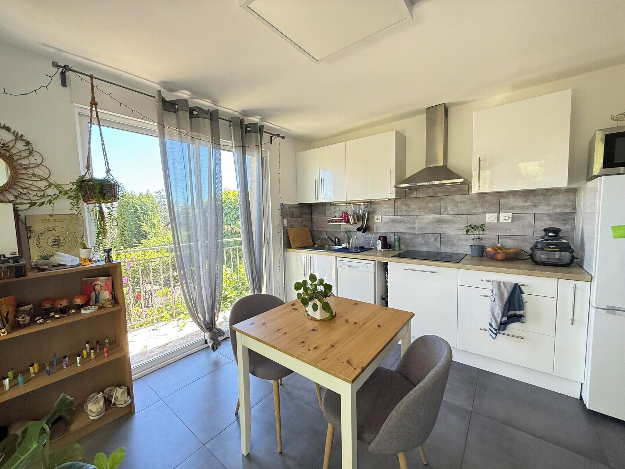 Een moderne keuken met witte kastjes, een houten tafel en uitzicht op groen.
