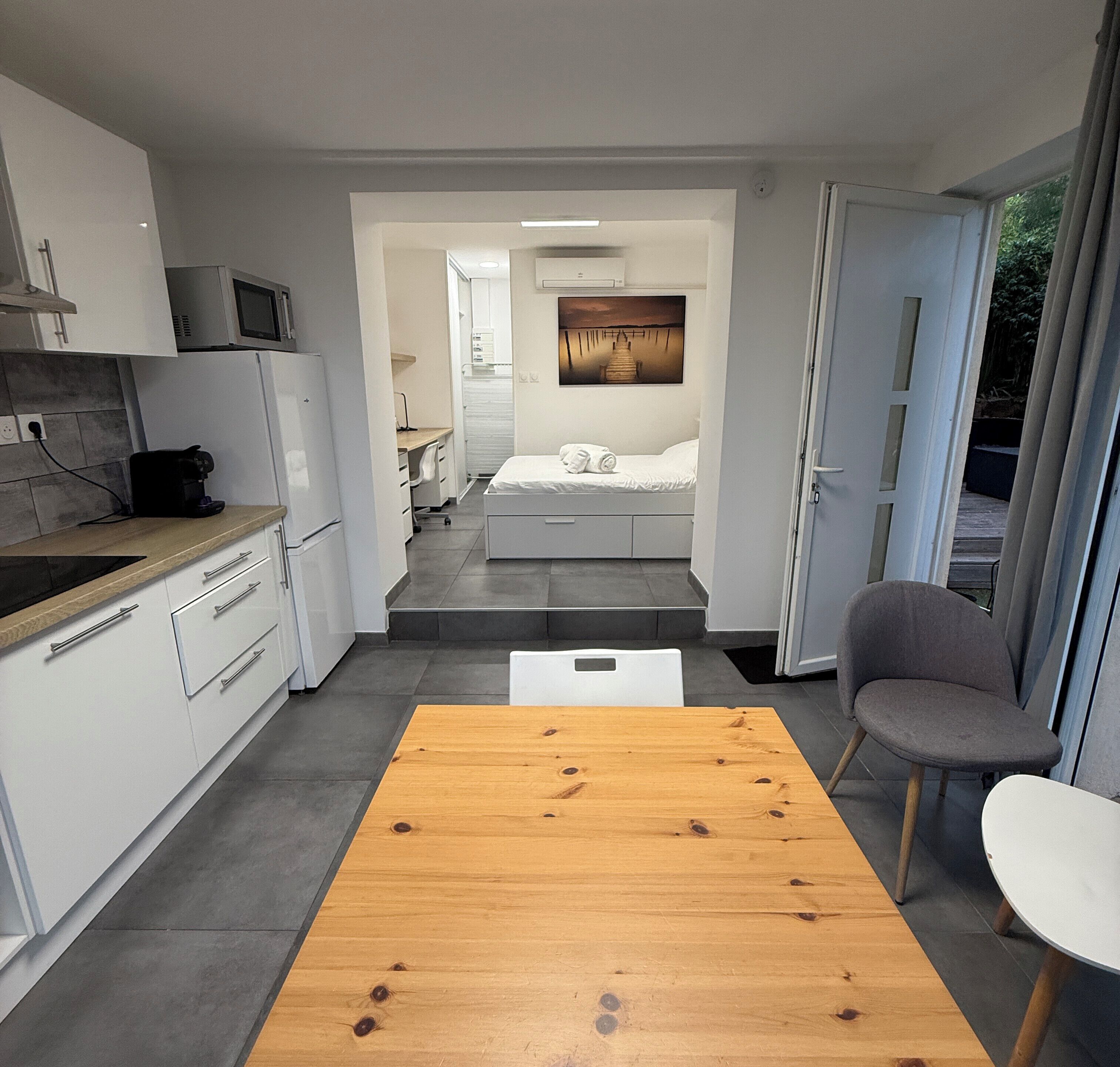 Een compacte, moderne kamer met kitchenette, een bed met uitzicht en een eethoek.