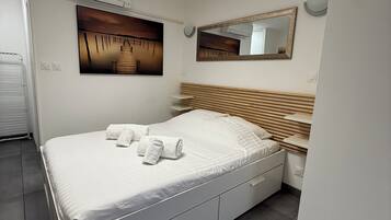 Une chambre à coucher moderne avec un lit, un tableau, un miroir et un radiateur encastré.