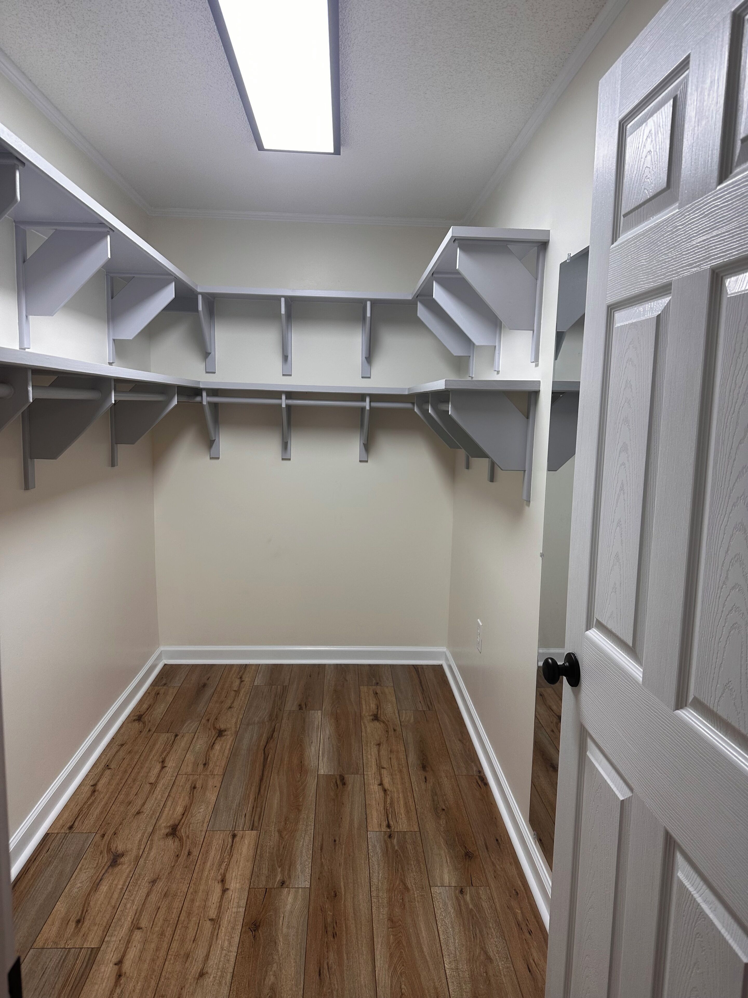 Una habitación con techo inclinado, piso de madera y estanterías empotradas.