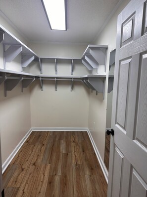 A room with a sloped ceiling, wooden flooring, and built-in shelving units.