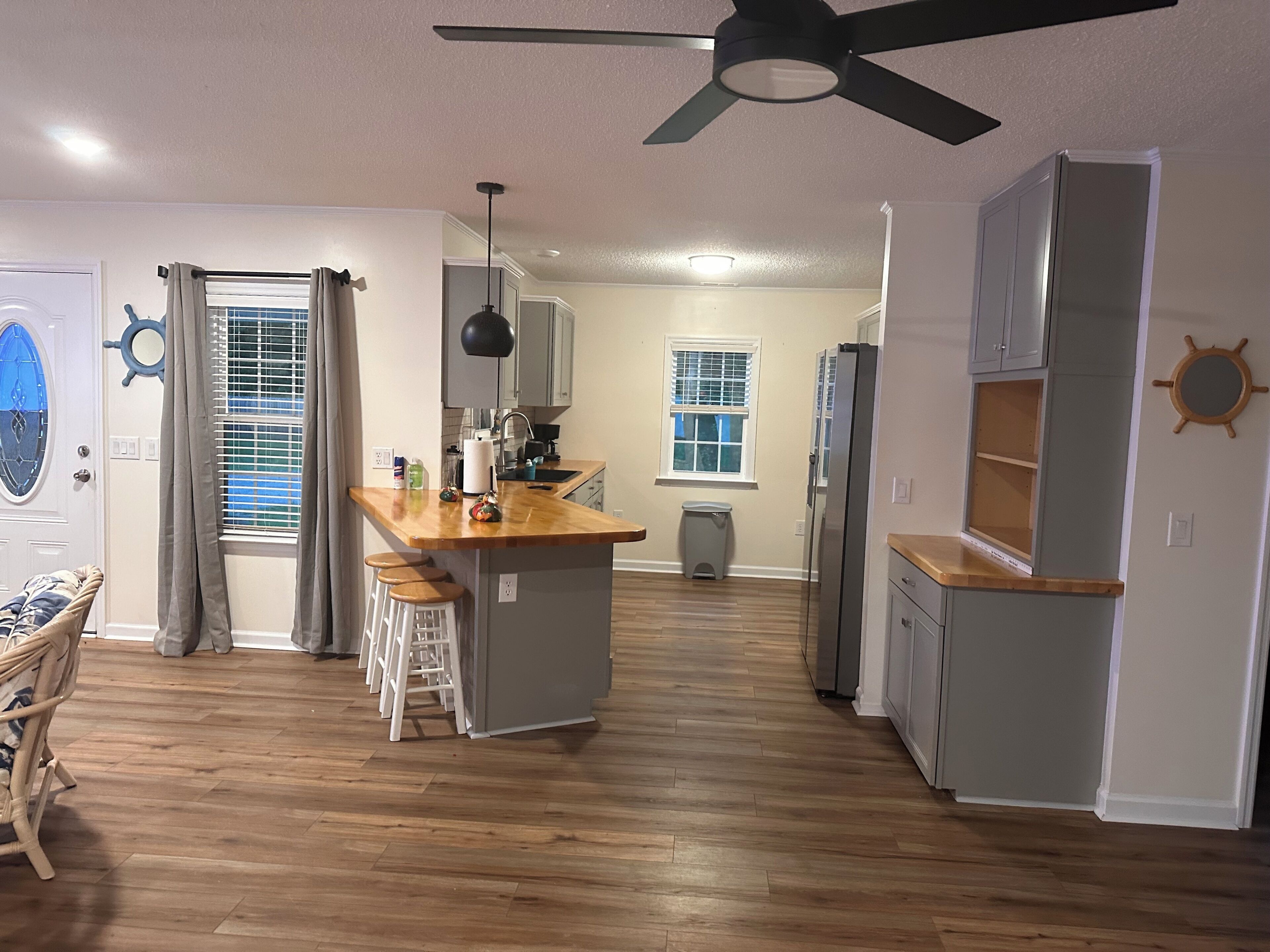 Una cocina moderna con una isla central, piso de madera y un ventilador de techo.