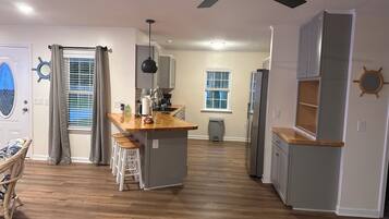 Una cocina moderna con una isla central, piso de madera y un ventilador de techo.