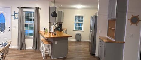 A modern kitchen with a central island, wooden flooring, and a ceiling fan.