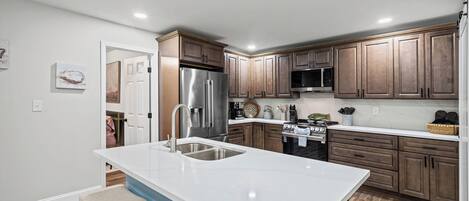 A modern kitchen with a central island, stainless steel appliances, and wooden cabinetry.