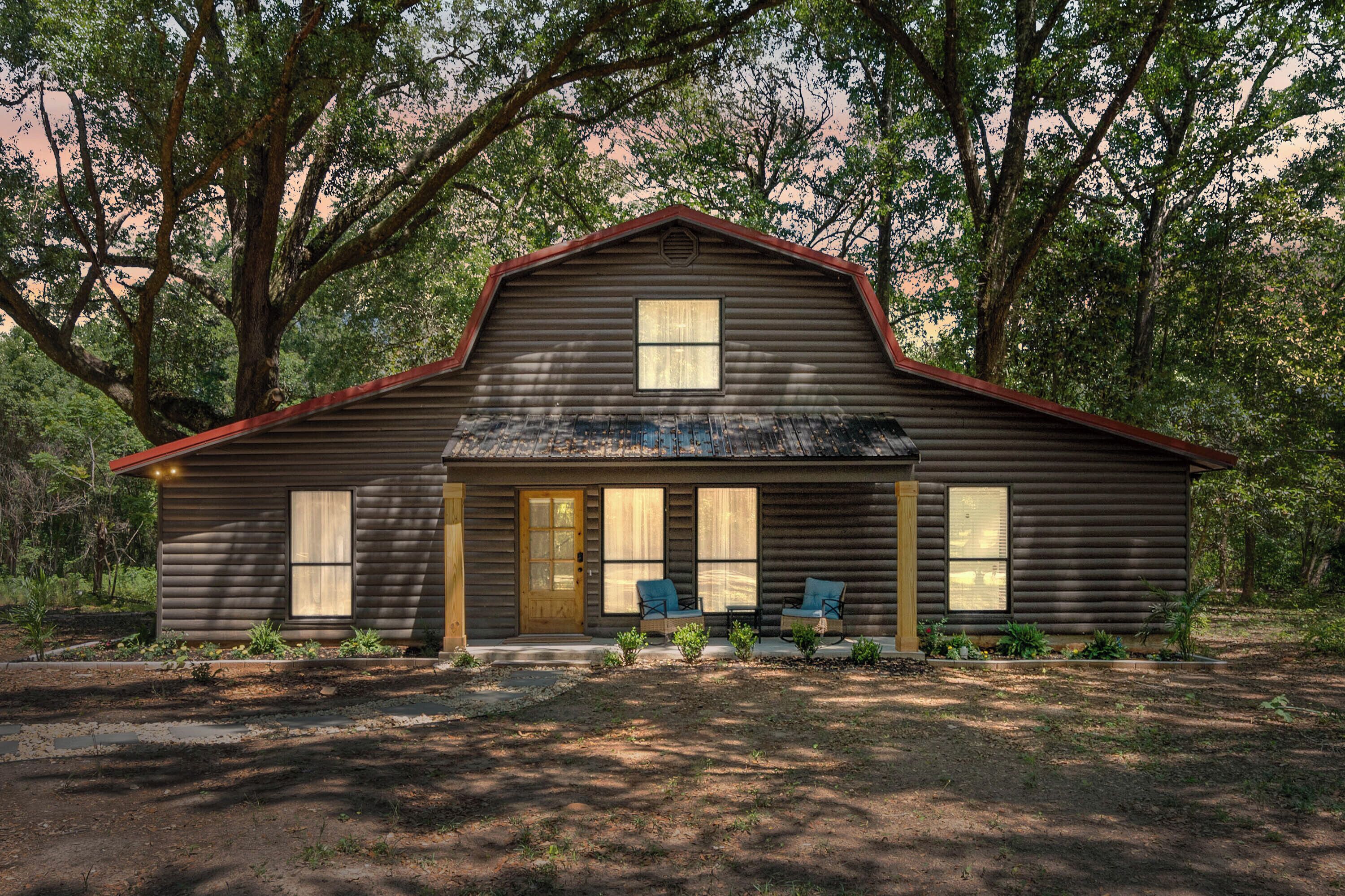 A log cabin with a front porch, two windows, and a door.