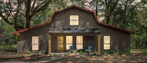 A log cabin with a front porch, two windows, and a door.