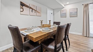 A dining room with a wooden table set for four, surrounded by leather chairs. - First Cast Foley - Fully Renovated Barn Home (Foley)