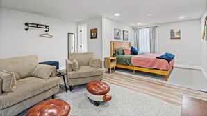 A bedroom with a bed, a sofa, a small table, and a hanging rack. - First Cast Foley - Fully Renovated Barn Home (Foley)