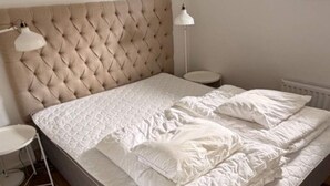 A bed with a tufted headboard, white bedding, and two bedside lamps.
