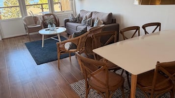 Una sala de estar con sofá, sillas, una mesa y vistas al exterior.