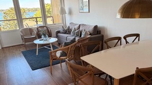 A room with a sofa, chairs, a dining table, a small round table, and a view of the outdoors.
