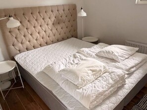 A neatly made bed with a tufted headboard, white bedding, and two bedside lamps. - 4 Star Holiday Home in Uddevalla (Uddevalla)