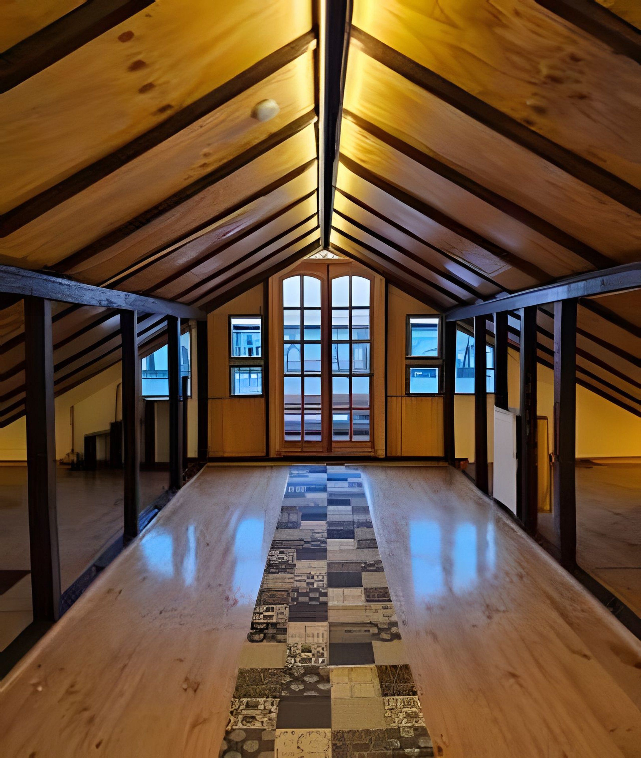 Habitación en ático con vigas de madera, piso a cuadros y ventanas amplias.