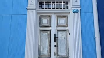 Una puerta blanca con un pequeño ventanal, flanqueada por paredes azules.
