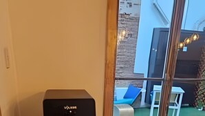 Dispensador de agua en una habitación con un ventanal grande, una silla blanca y un cojín azul.
