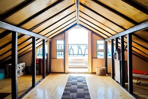 An attic room with a sloped ceiling, wooden beams, and a view of the outside. - Turquía Casa Fran Valparaíso (Valparaíso)