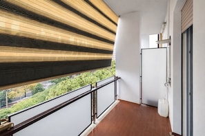 Ein Balkon mit Blick auf Grünflächen und ein Gebäude.