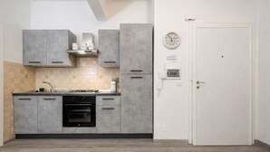 A kitchen with grey cabinets, a stove, oven, and a white door. - Cozy Urban Retreat | 2BR | Family Getaway in Rome (Rome)