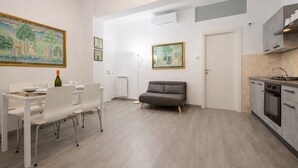 A modern apartment with a dining area, a sofa, a kitchen, and two paintings on the walls. - Cozy Urban Retreat | 2BR | Family Getaway in Rome (Rome)