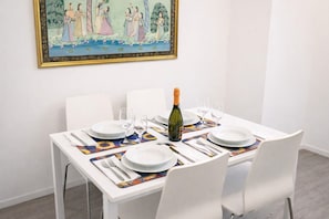 Uma mesa de jantar posta com pratos brancos, copos de vinho e uma garrafa de champanhe.