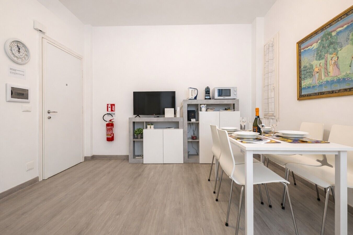 Eine moderne Küche mit Flachbildfernseher, Mikrowelle und einer kleinen Essecke mit Tisch für zwei Personen.