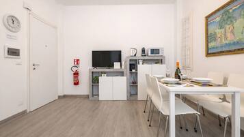 Eine moderne Küche mit Flachbildfernseher, Mikrowelle und einer kleinen Essecke mit Tisch für zwei Personen.